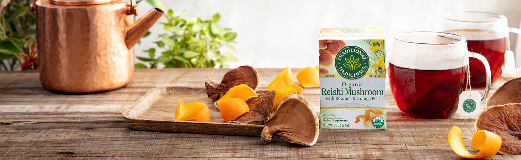Reishi tea steeping next to fresh reishi mushrooms and orange peel