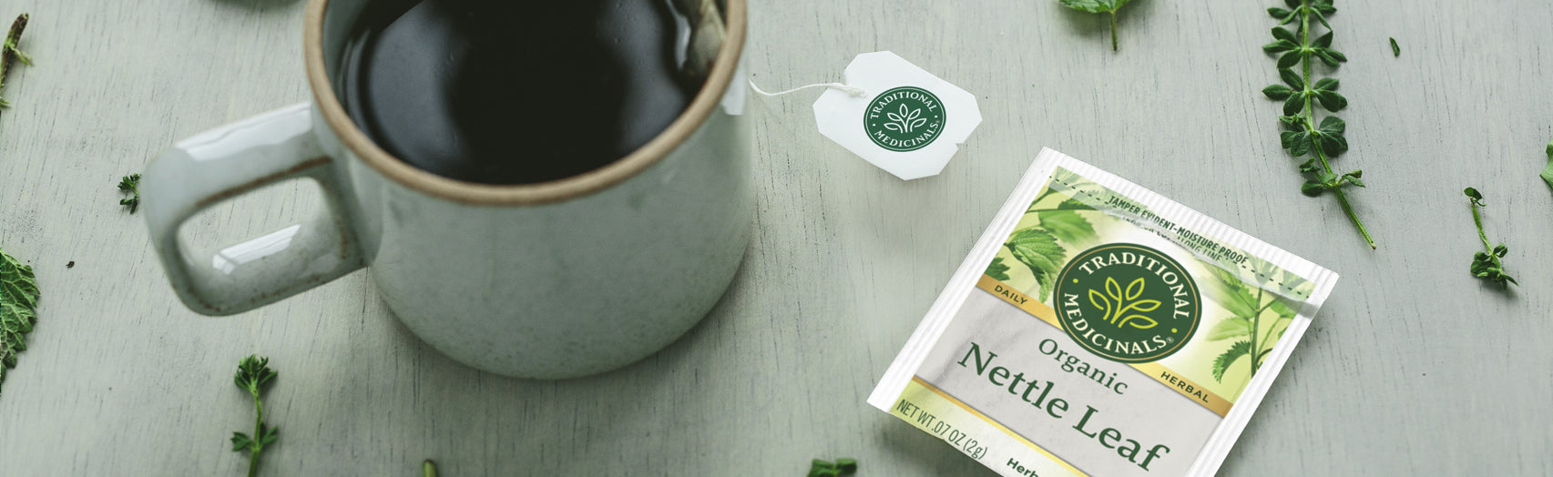 Cup of steeping Nettle Leaf tea next to a Nettle Leaf tea overwrap